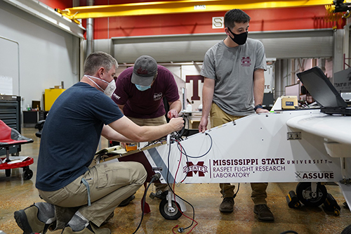 Matt Newburn, from left, of ARM, along with Connor White and Miles Ennis, both of Raspet Flight Research Lab, integrate instrumentation into a TigerShark unmanned aircraft. (Photo by Chris Bryant)