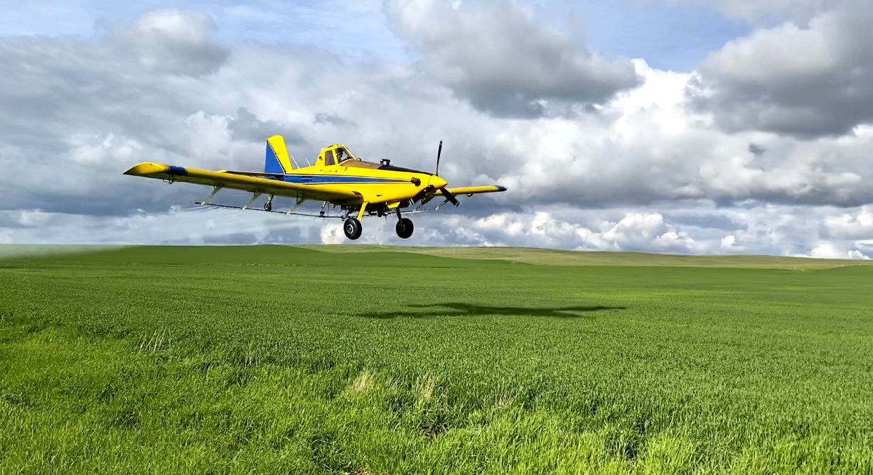 A turbine-powered ag plan makes a spray pass over a field. 