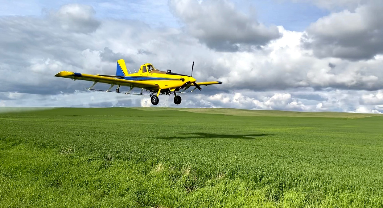 A turbine-powered ag plan makes a spray pass over a field.