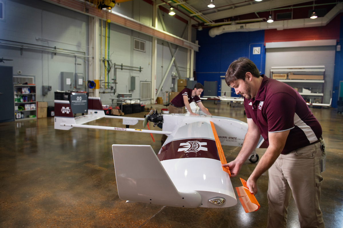 Two engineers apply 3D printed ice shapes to the leading edges of unmanned aircraft system wings.